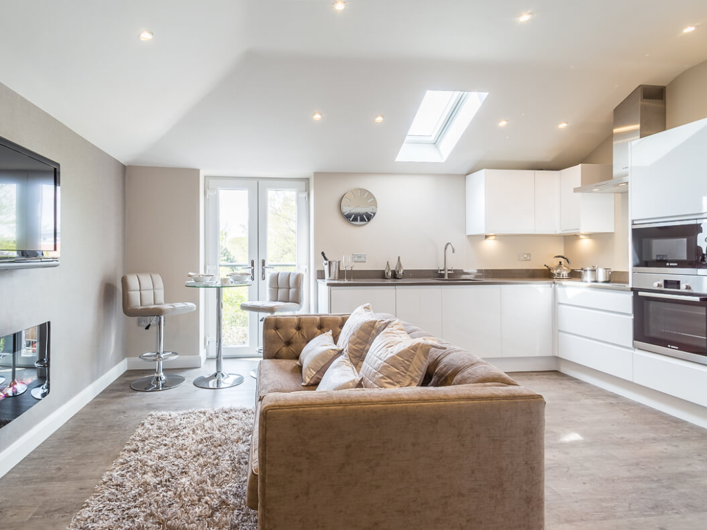 A modern light filled apartment interior with a kitchen to the right