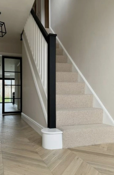a black stair post leads up a white staircase